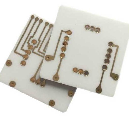 Two white ceramic circuit boards with patterned conductors and circular pads